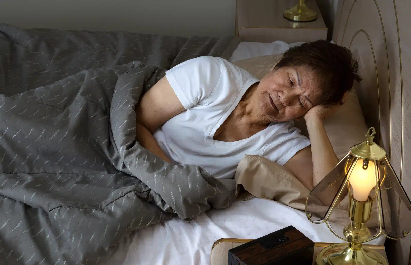 woman with insomnia lays in bed on her side