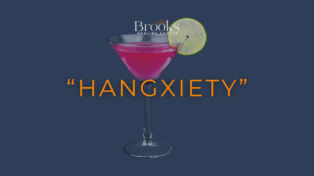 Pink cocktail with a lime slice and “Hangxiety” text beneath the Brooks Healing Center logo, illustrating anxiety after drinking.
