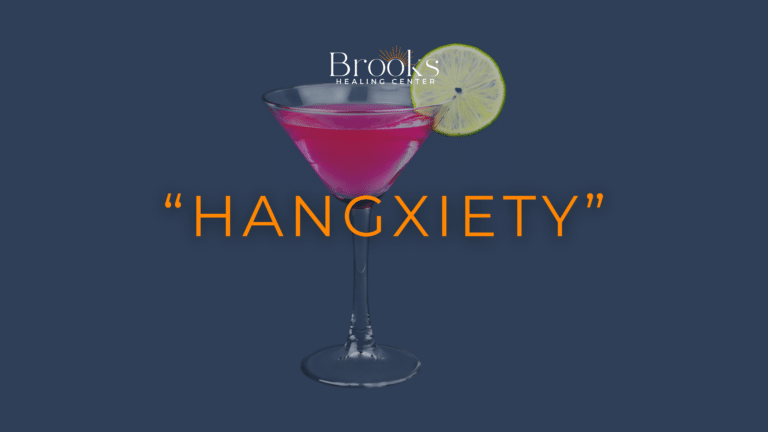 Pink cocktail with a lime slice and “Hangxiety” text beneath the Brooks Healing Center logo, illustrating anxiety after drinking.